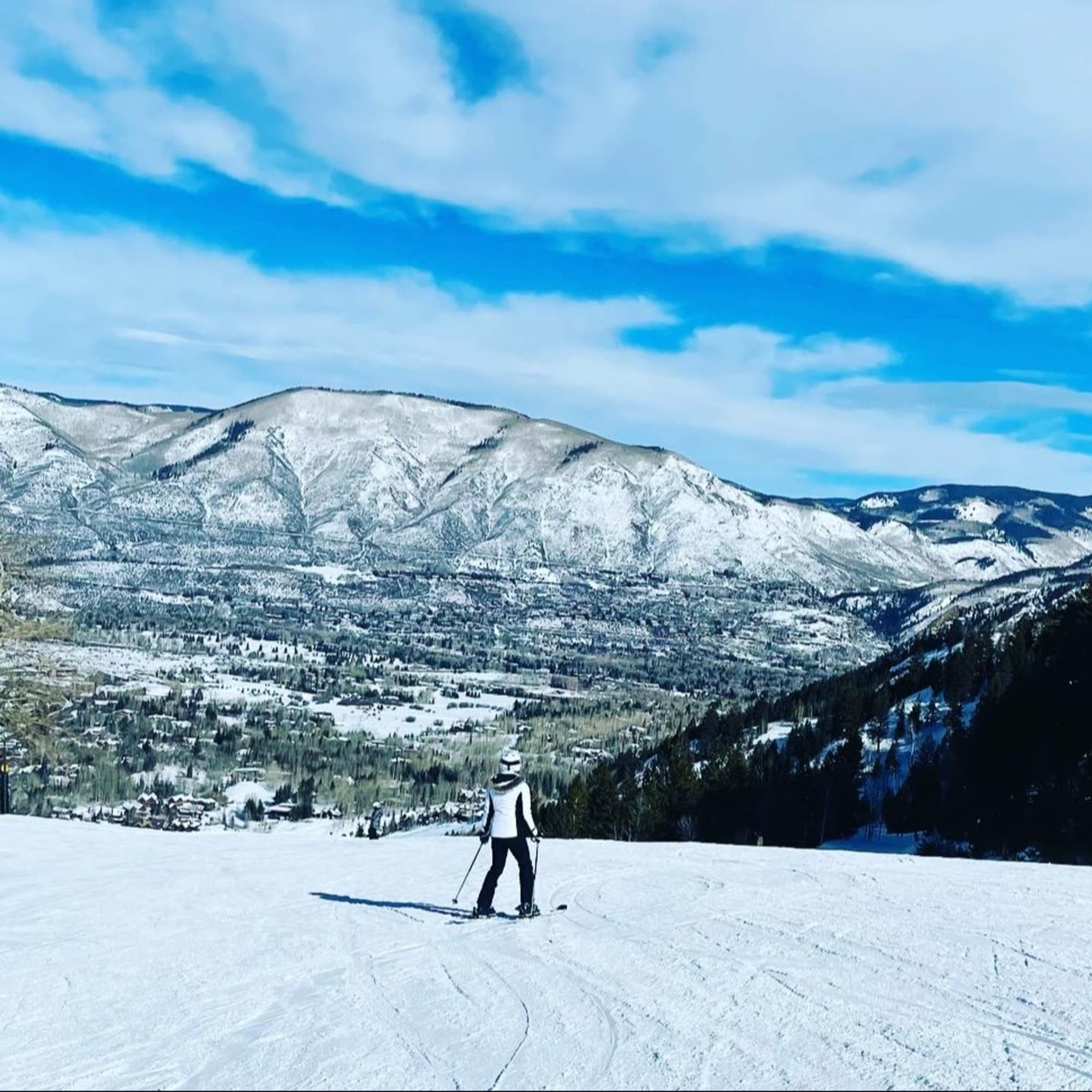 A girl standing on a snowy mountain during daytime.