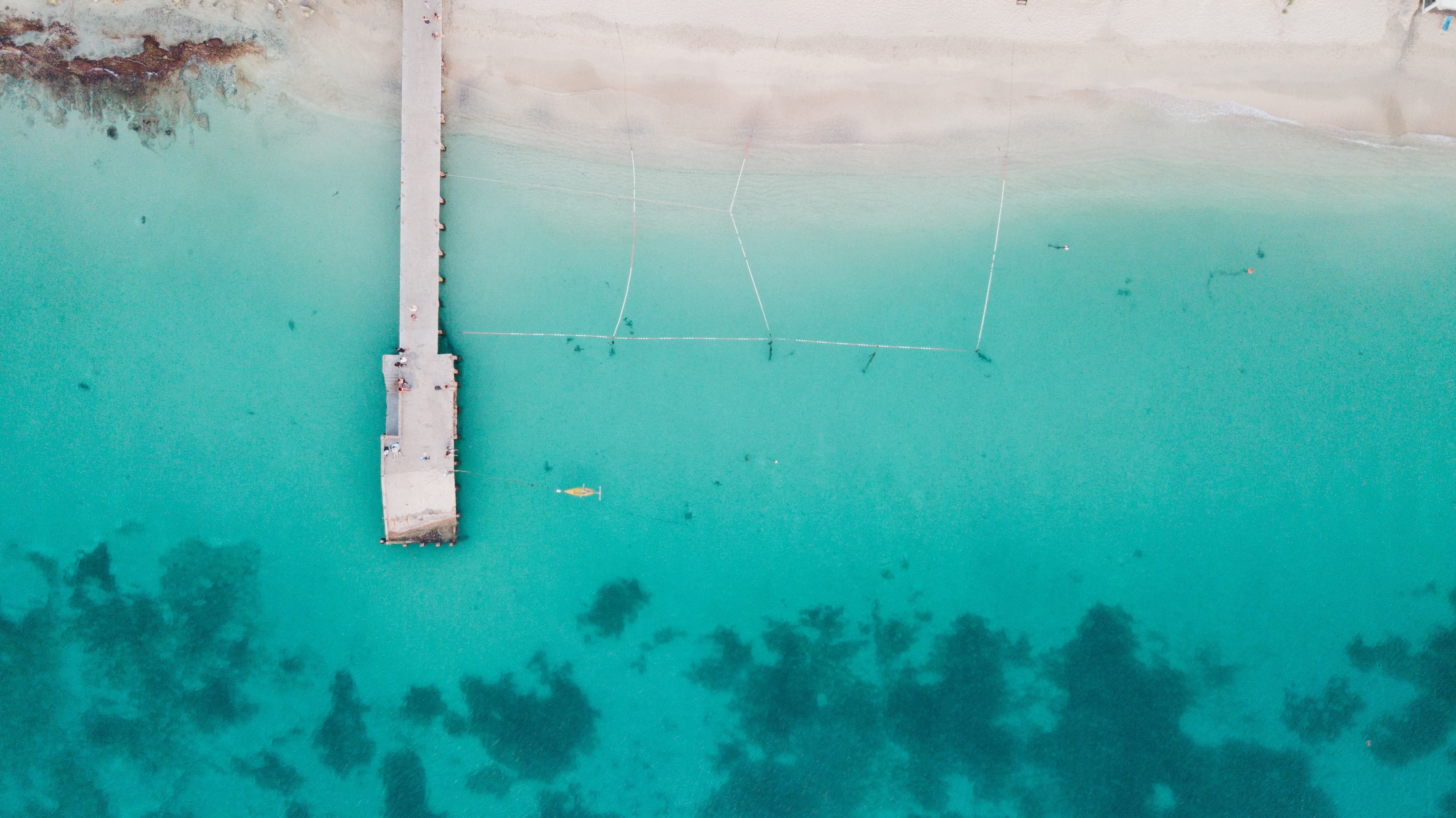 An aerial view of Saint Martin with crystal blue water and a white dock.