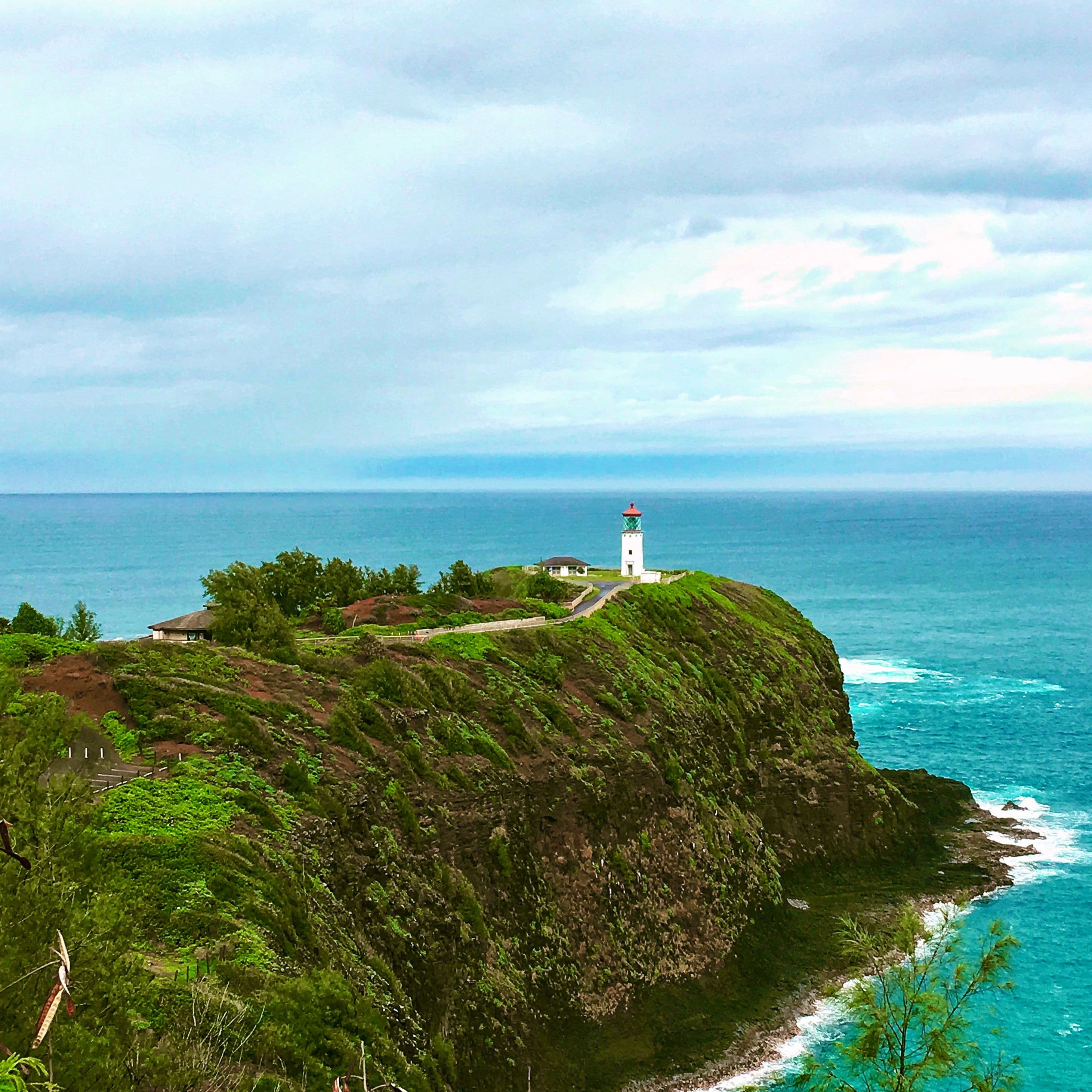 large green body of land with a lighthouse with cloudy skies