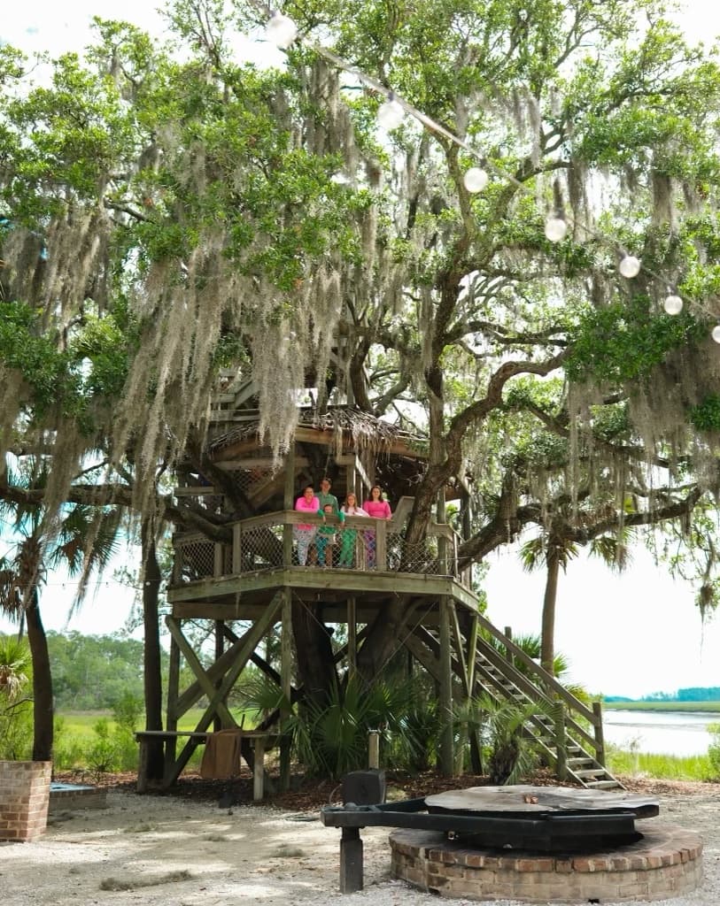 family stands in a treehouse in the forest in Palmetto.