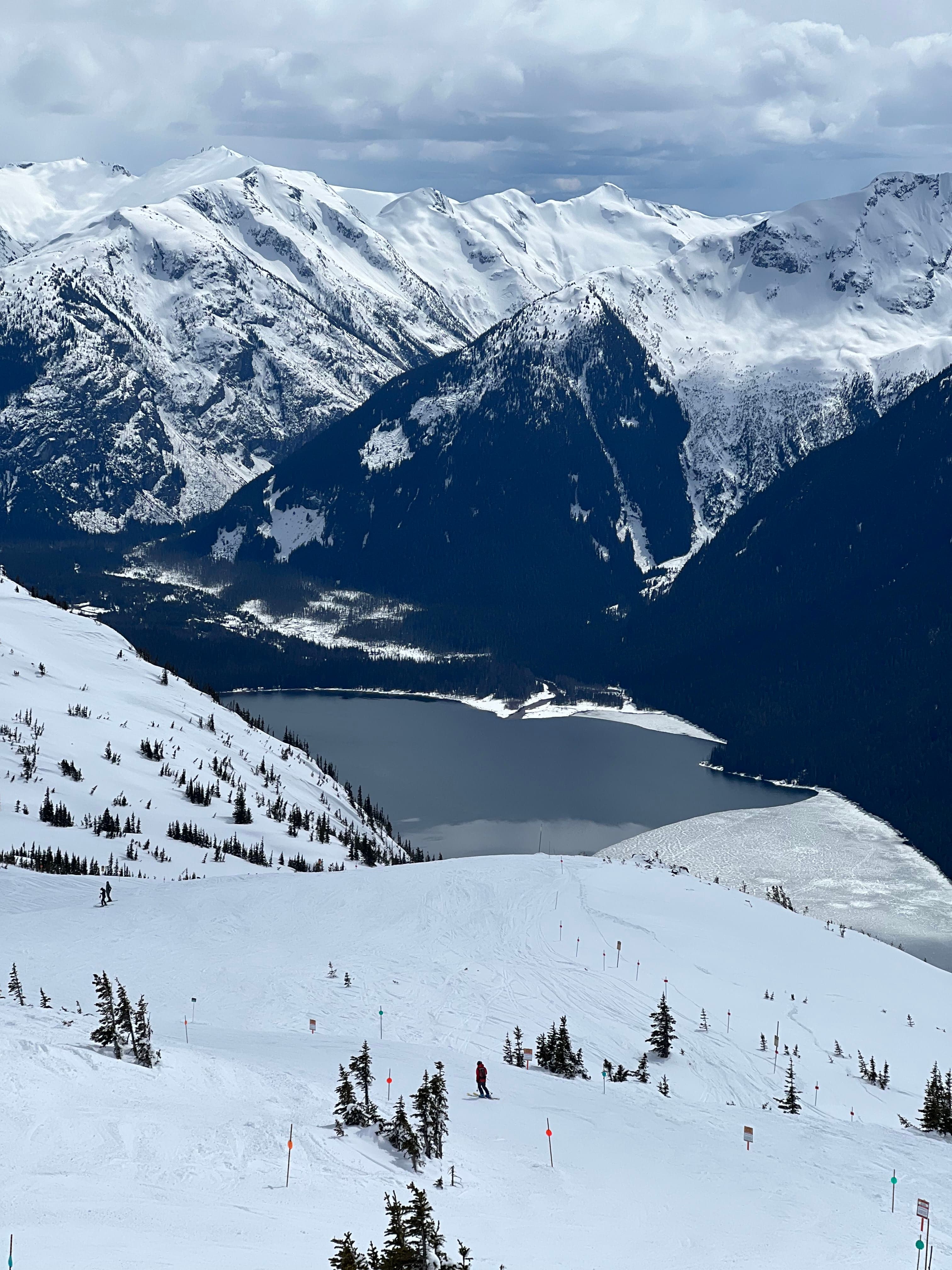 Snowy mountain with body of water during daytime
