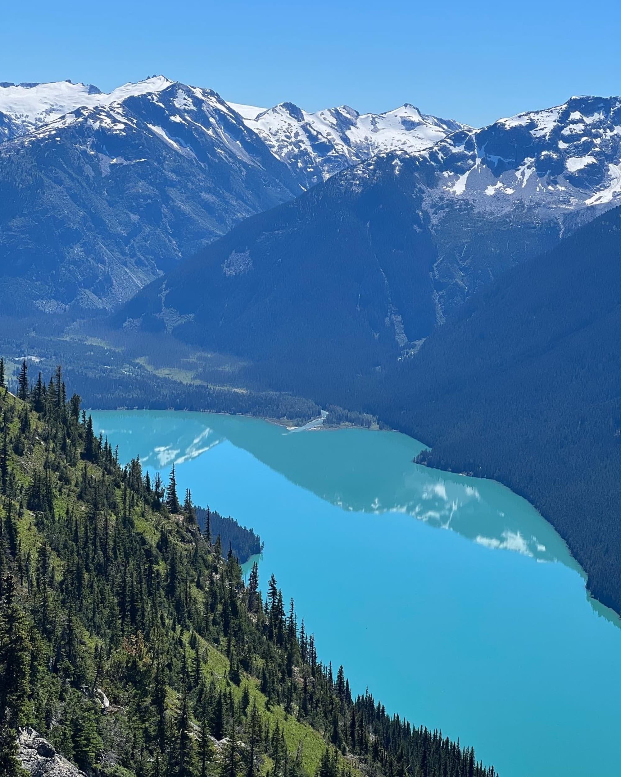 a light blue lakes runs though large mountain range