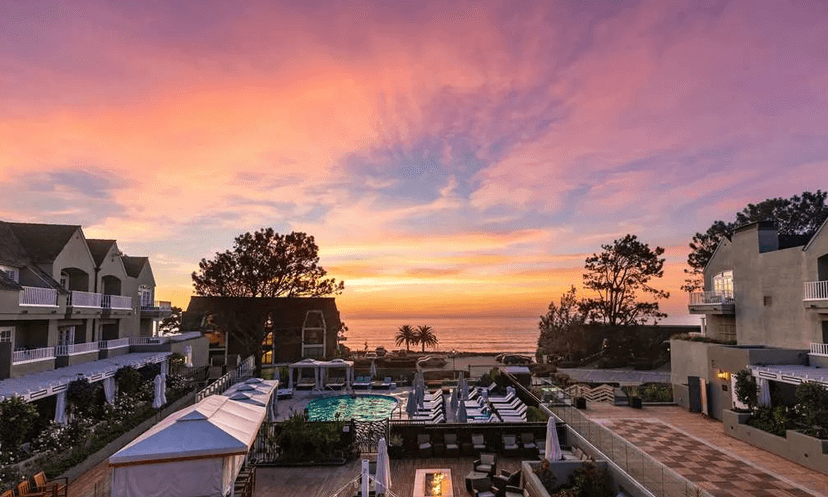 The pool area at L'Auberge del Mar in between hotel buildings and the beach at sunset.