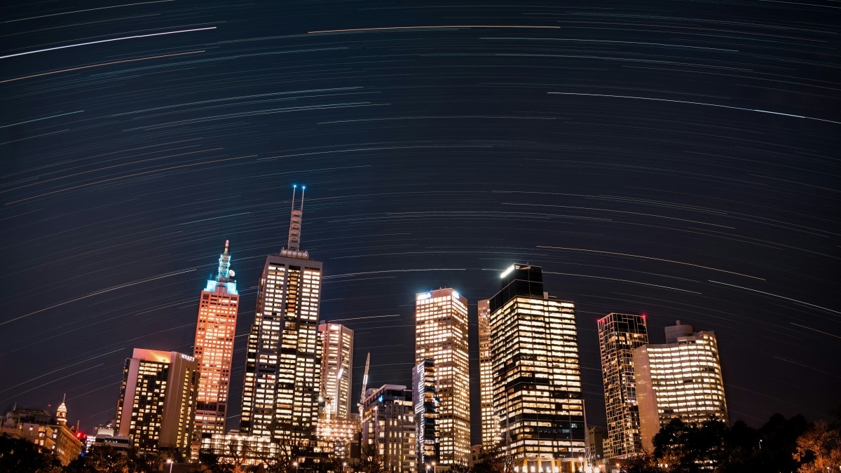 The Melbourne city skyline at night with a time-lapse of stars passing overhead.