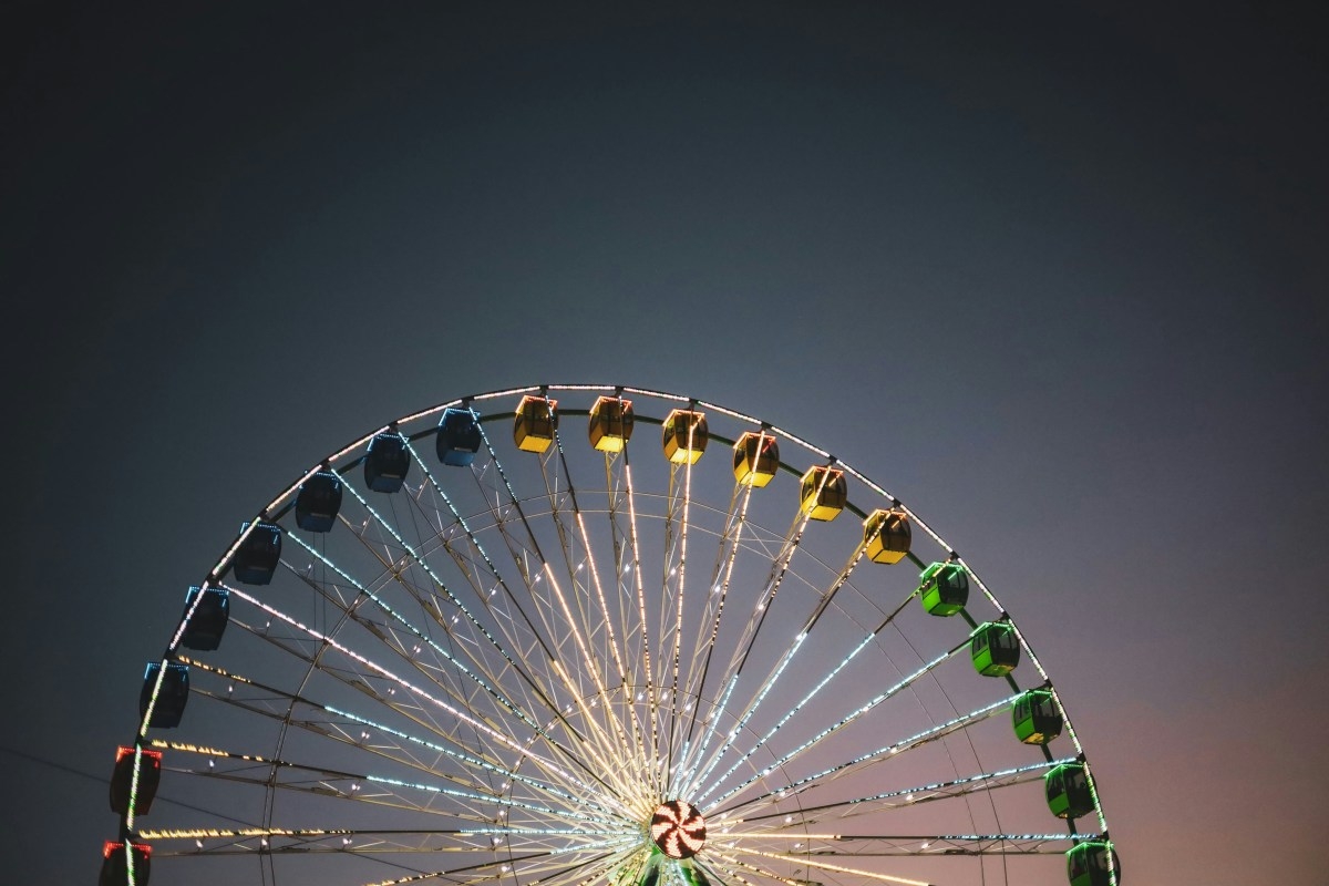 Illuminated ferris wheel against the evening sky at sunset.