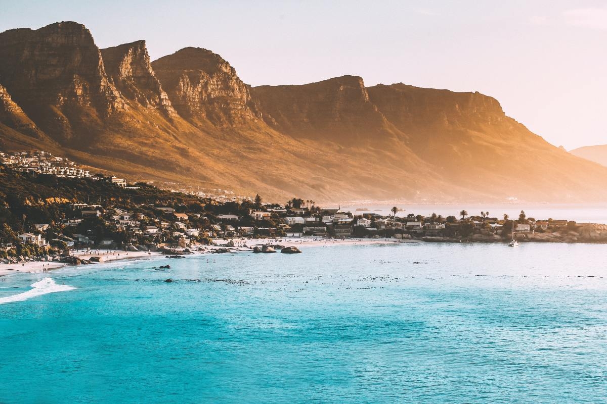 View of Cape Town in front of towering mountain ranges on ocean in South Africa. 