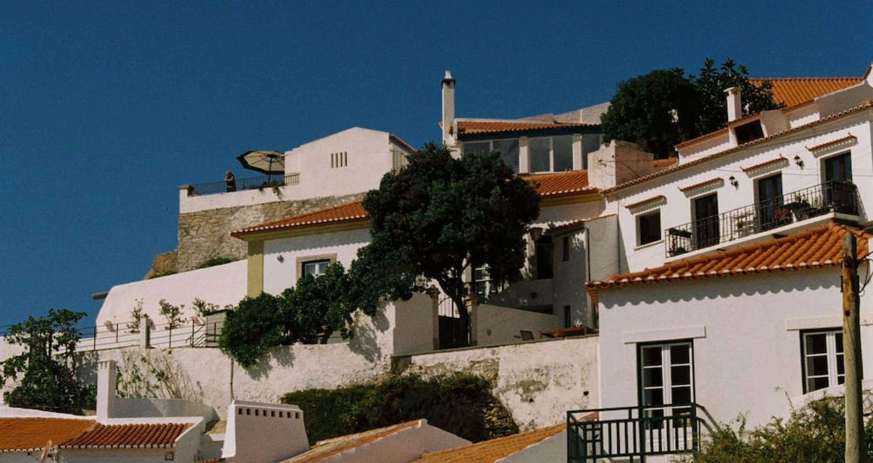 a hillside collection of white stucco houses with red tiled roofs