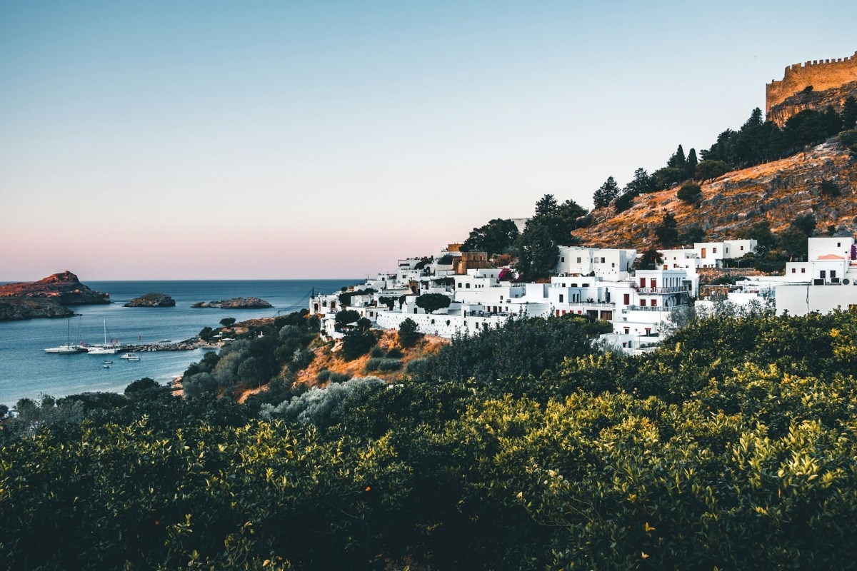 White buildings on a cliff above the ocean.