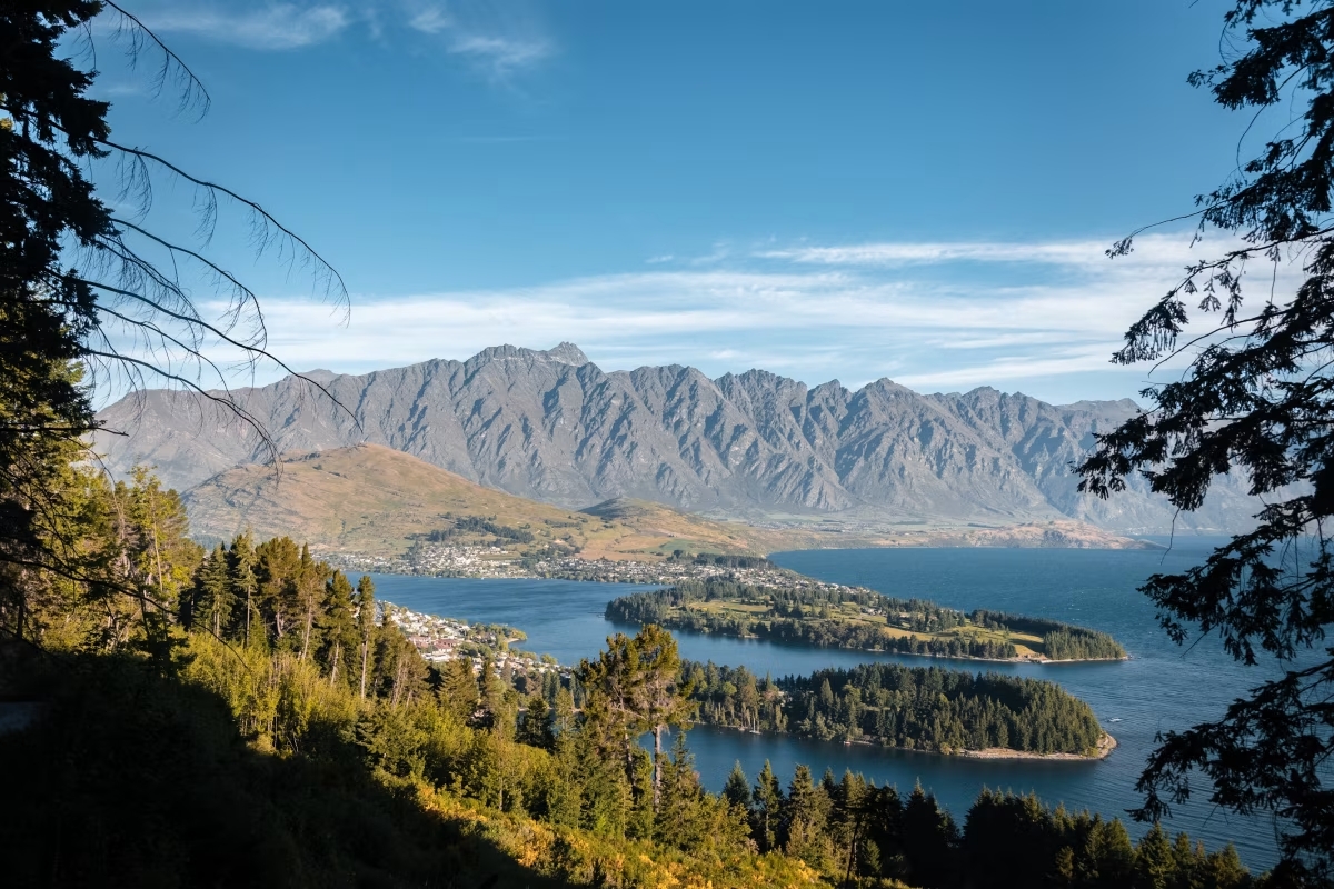 A view over a lake surrounded by forests and mountains.