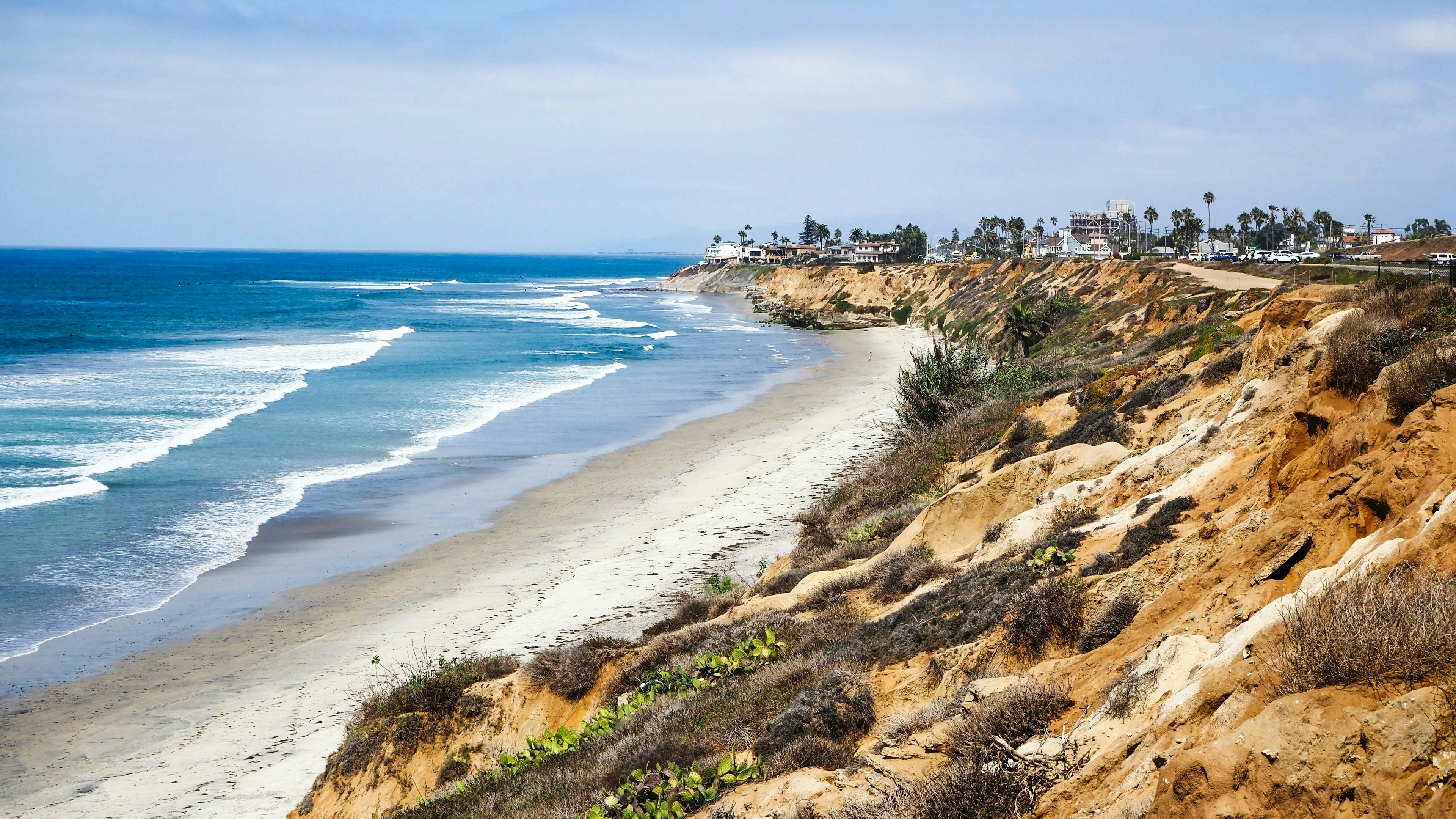 A brown and green hillside next to the blue ocean.