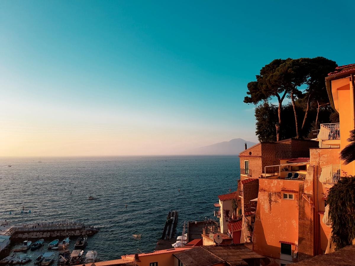 Orange buildings of Sorrento facing blue sky and ocean.