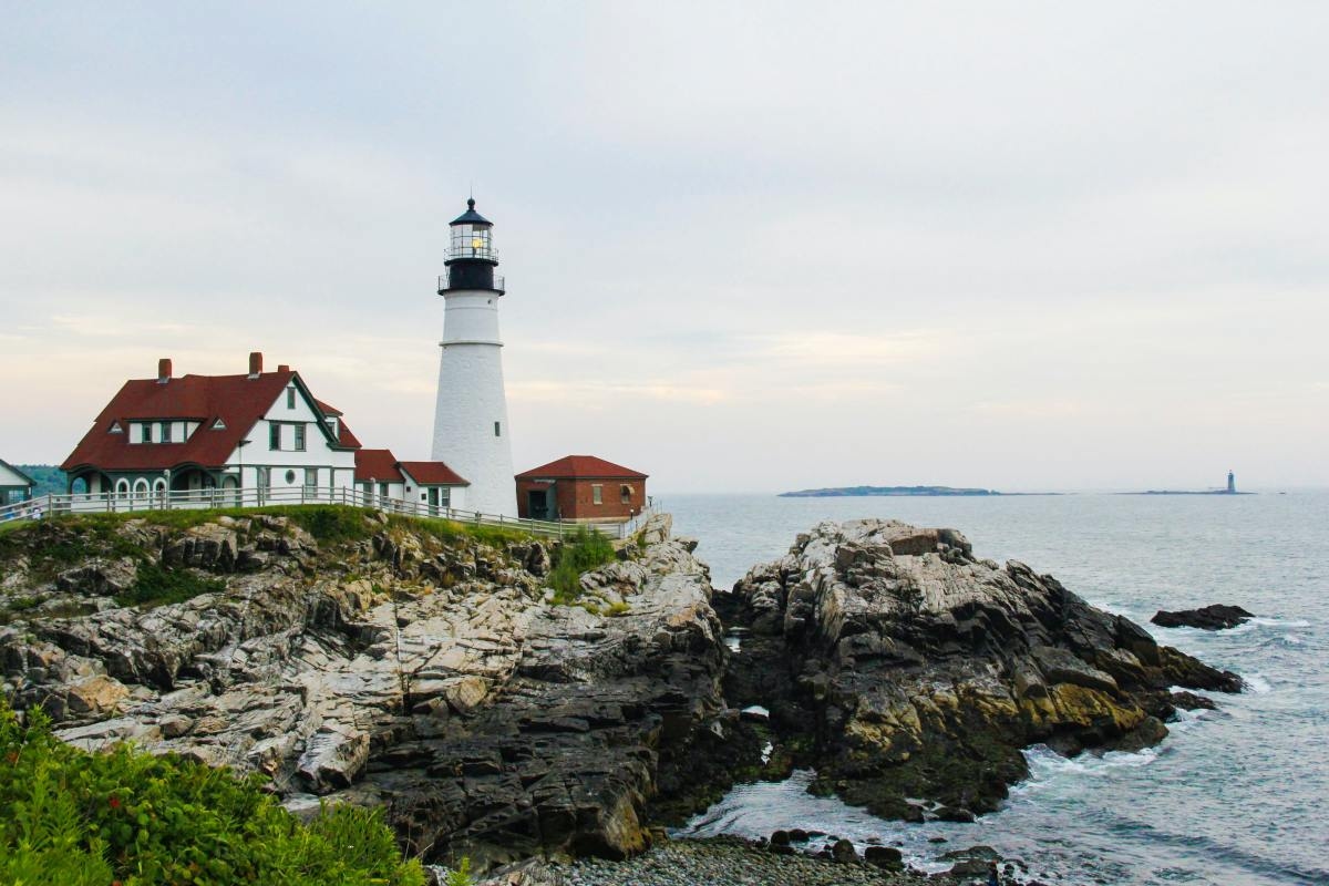 Lighthouse by ocean on a cloudy day in Maine.