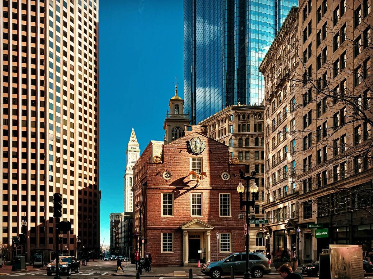 Red brick building and historic buildings in front of taller modern skyscrapers.