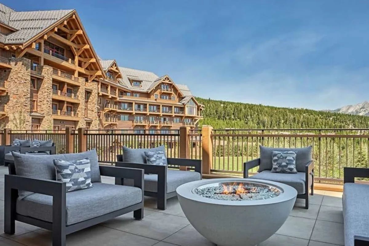 terrace with fire pit and lounge chairs with hotel and mountains in the background