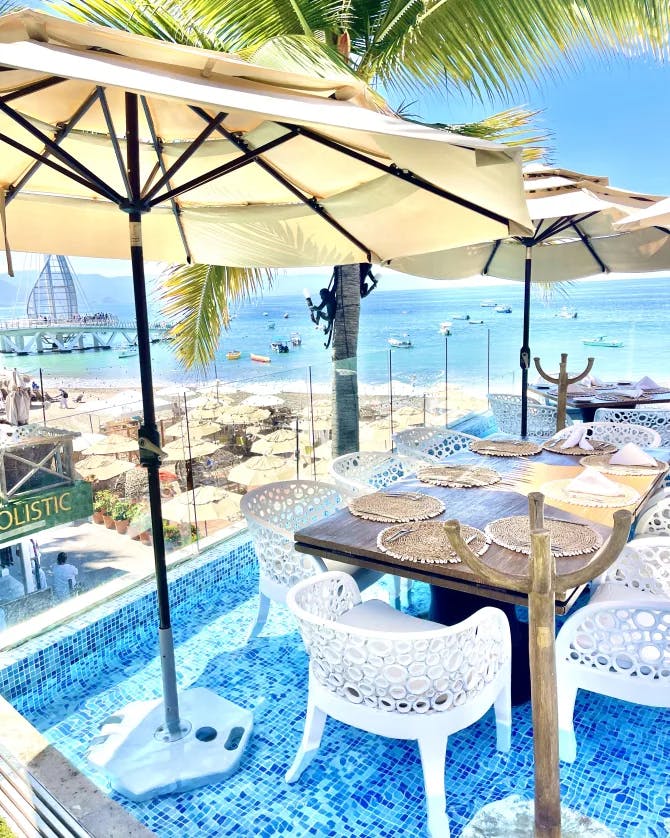 A table setting outside with the ocean in the distance on a sunny day.