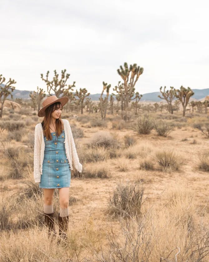 Posing for a picture in desert wearing a blue dress and brown hat