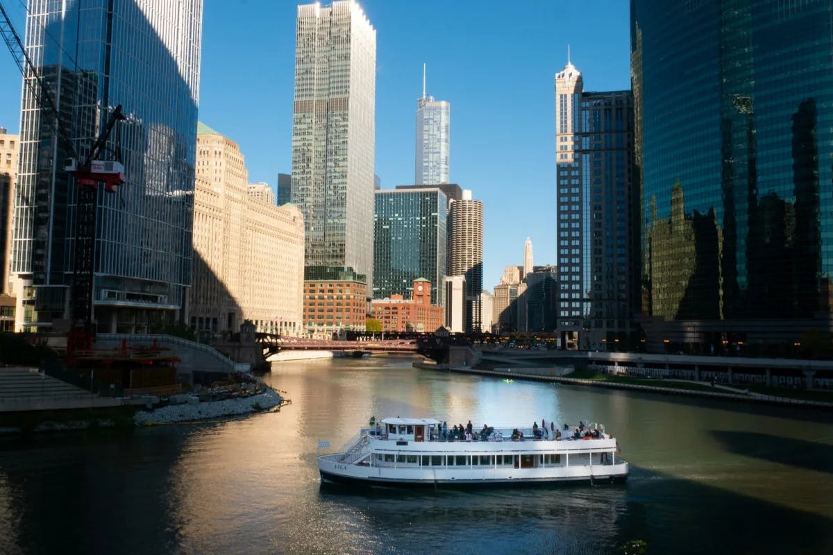 A white boat on a river with city buildings in the background