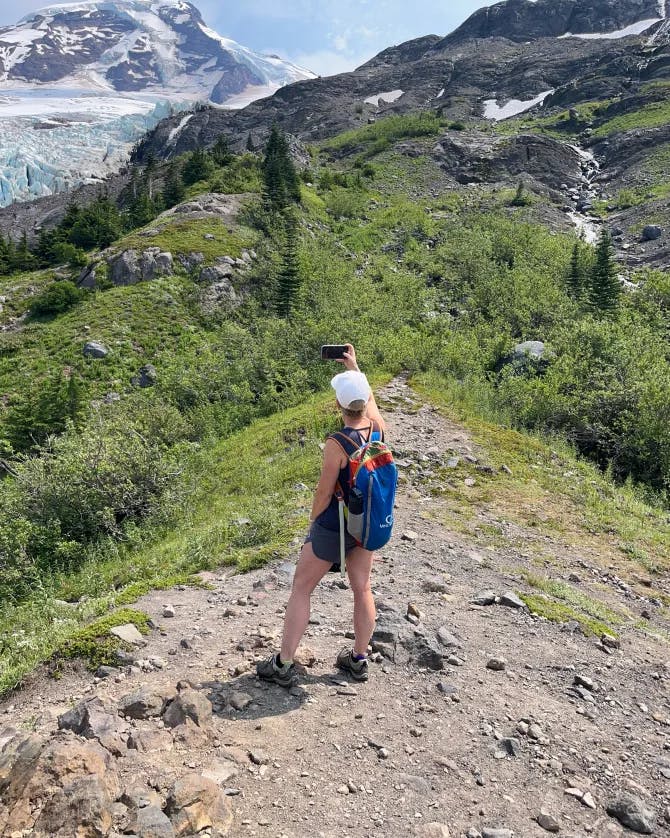 Advisor Michelle McDaniel-Bielat taking a photo during a hike of mountainous landscape.