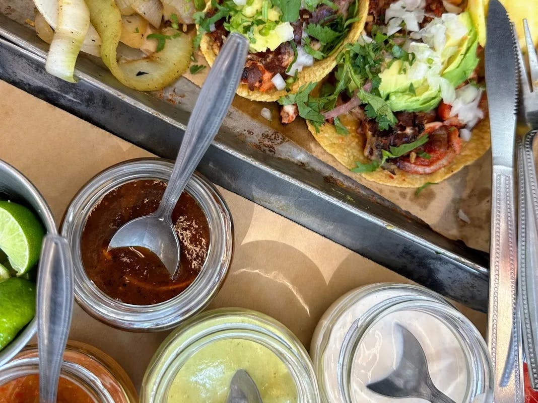 Close up photo of tacos and jars of sauces