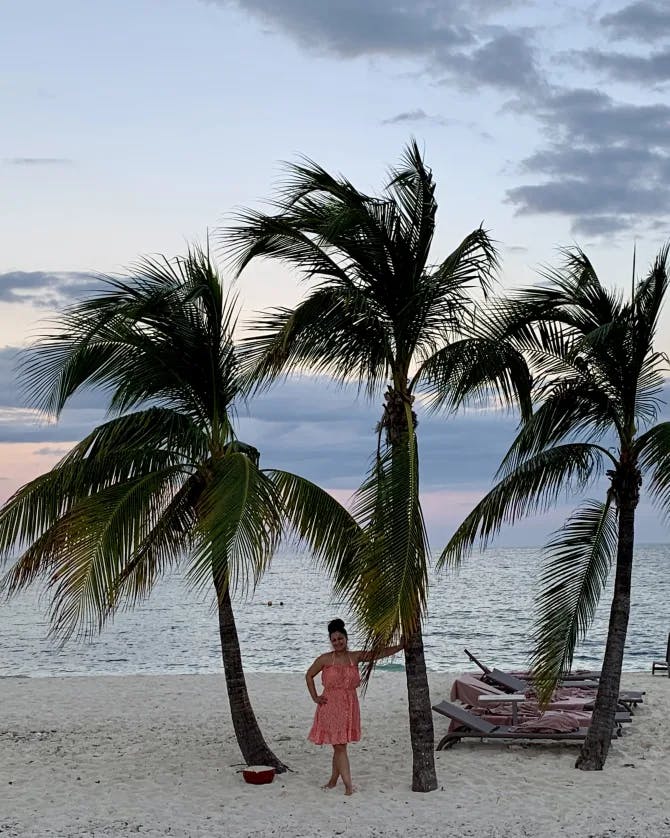 Picture of Ashley standing with palm treem on a beach