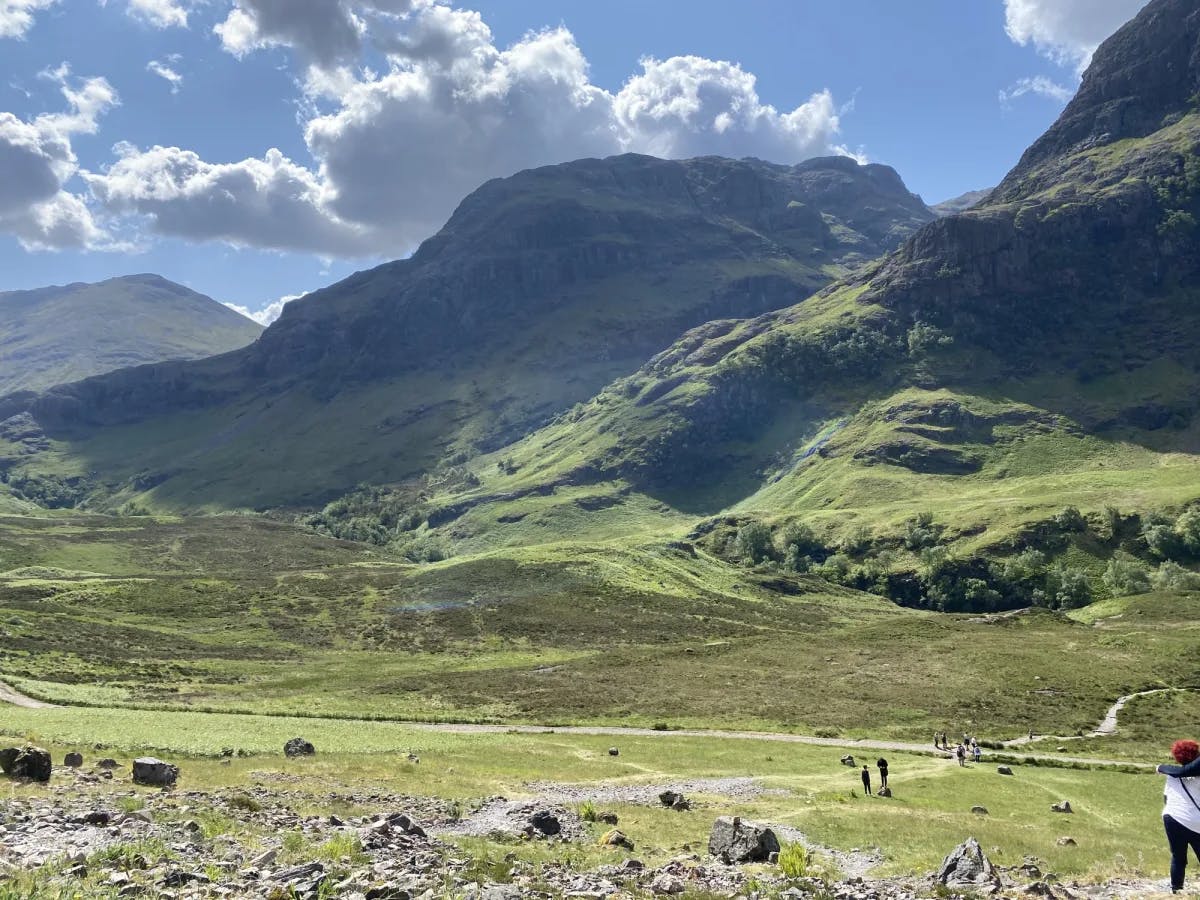 A valley beneath green mountains dotted with hairy coos.