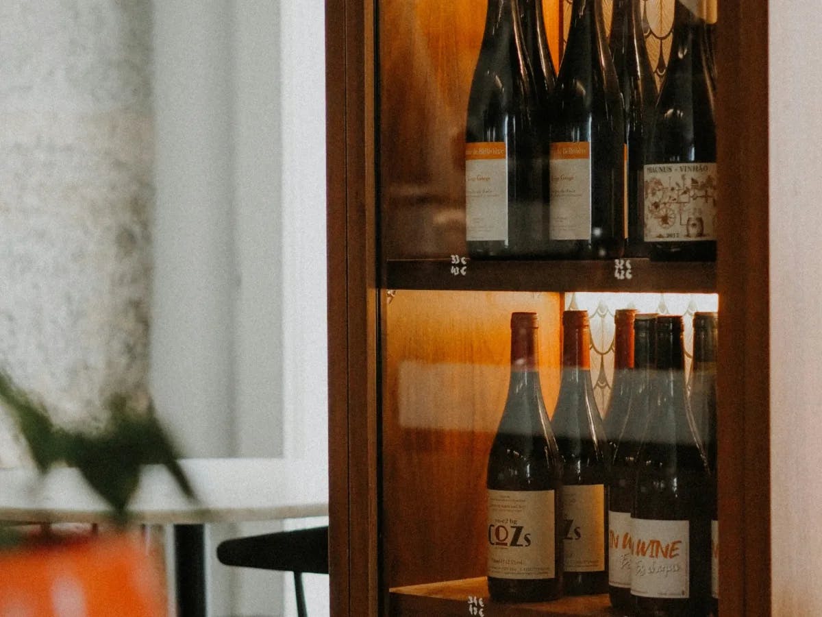 A shelf with multiple wine bottles that are decoratively backlit. 