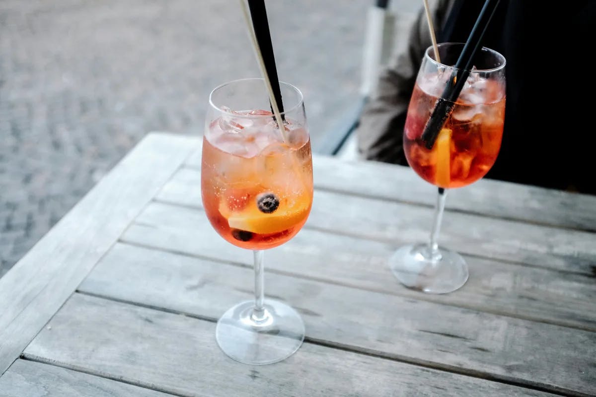 Two Aperol spritzes on a wooden table.