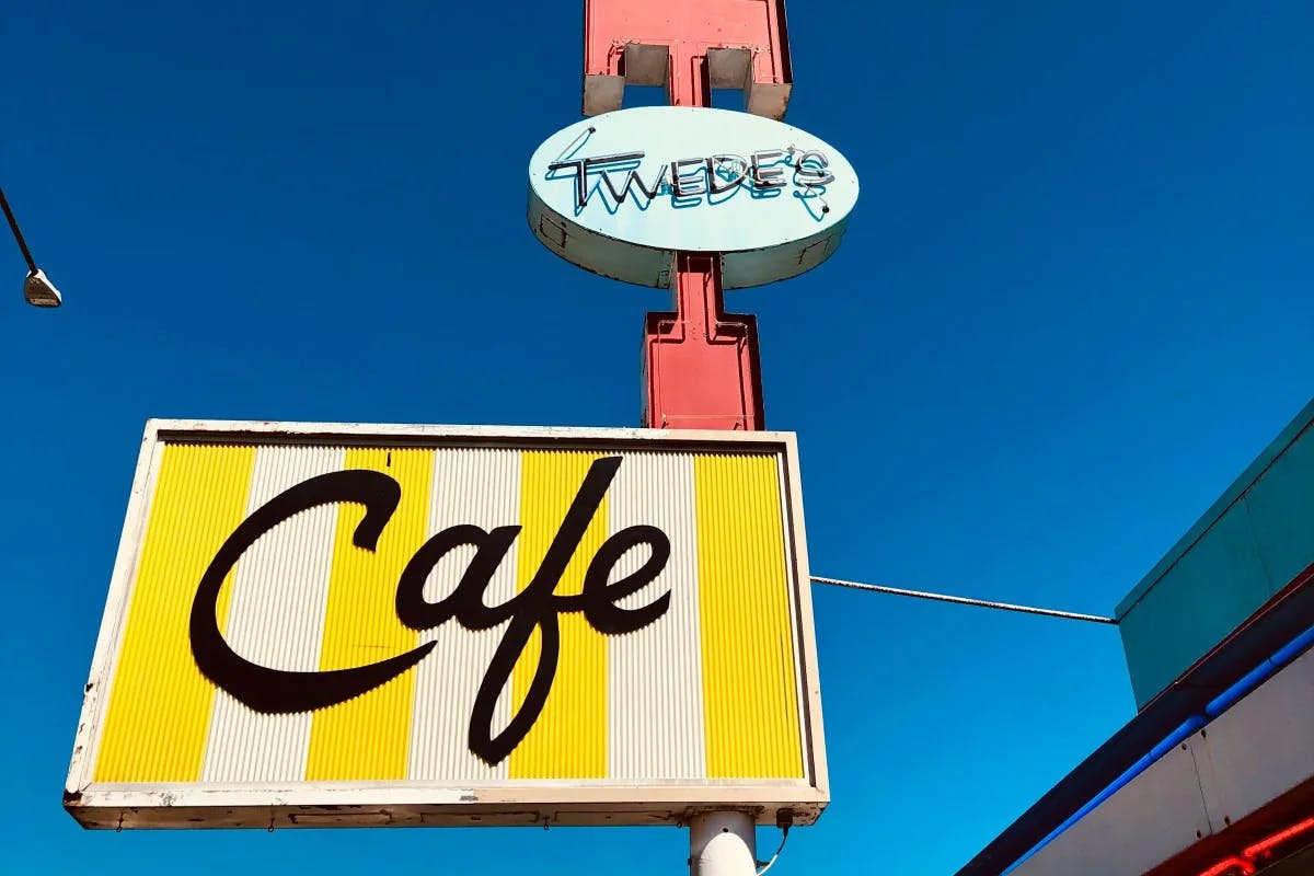 A close-up view of the Twede's Cafe sign, with a clear blue sky behind it.