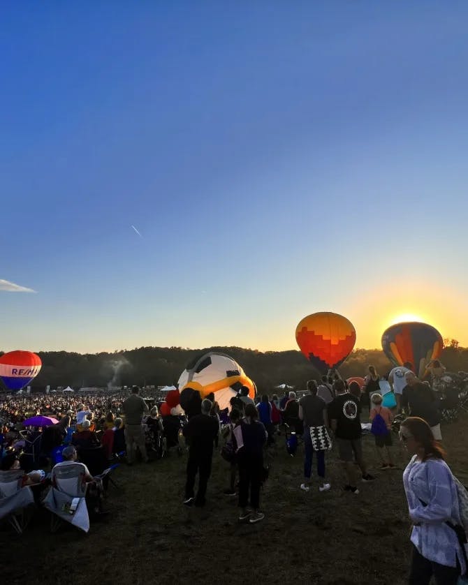 Hot air balloons on ground surrounded by people.