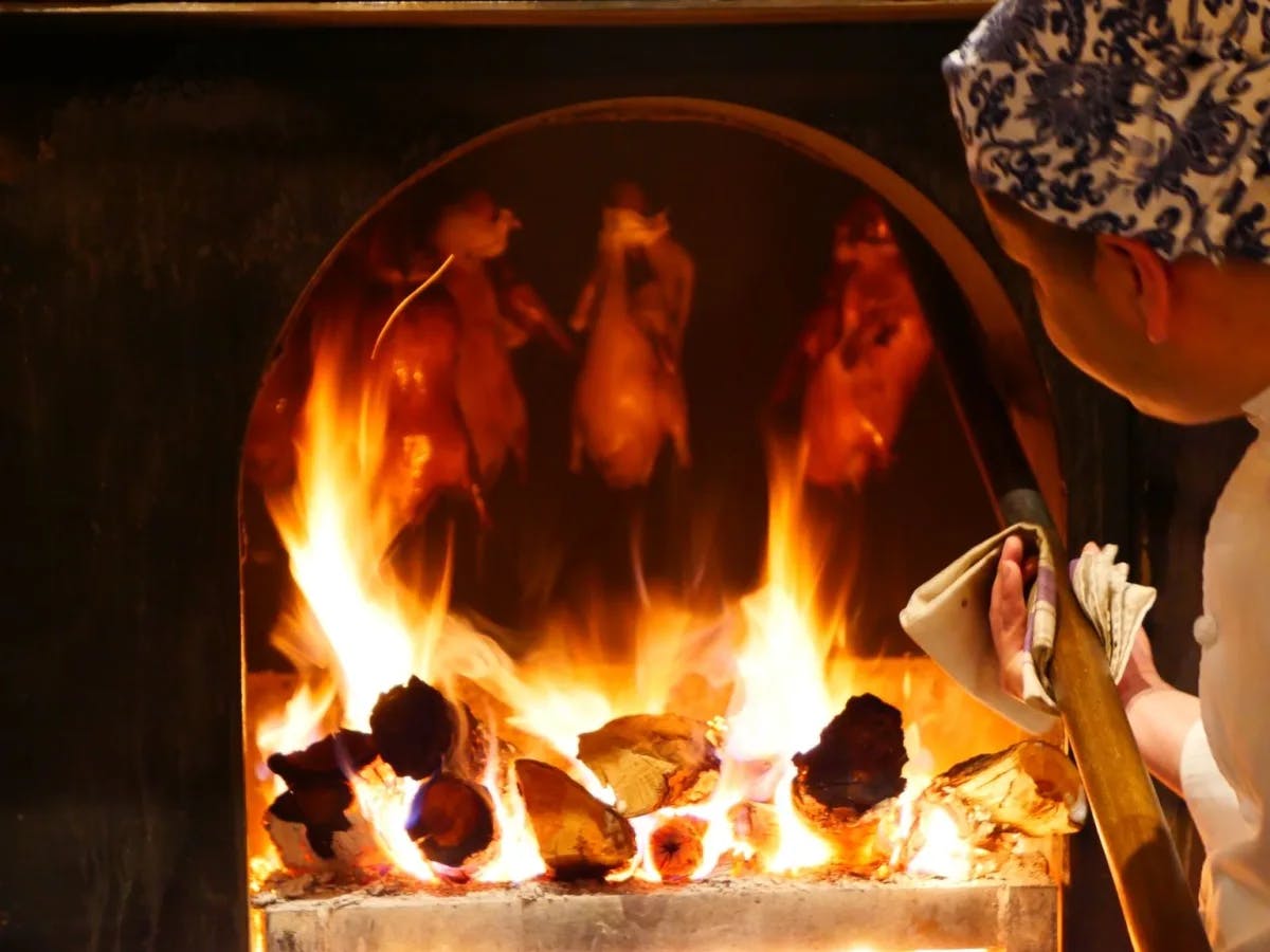 A woman is putting bread in the furnace at a restaurant.