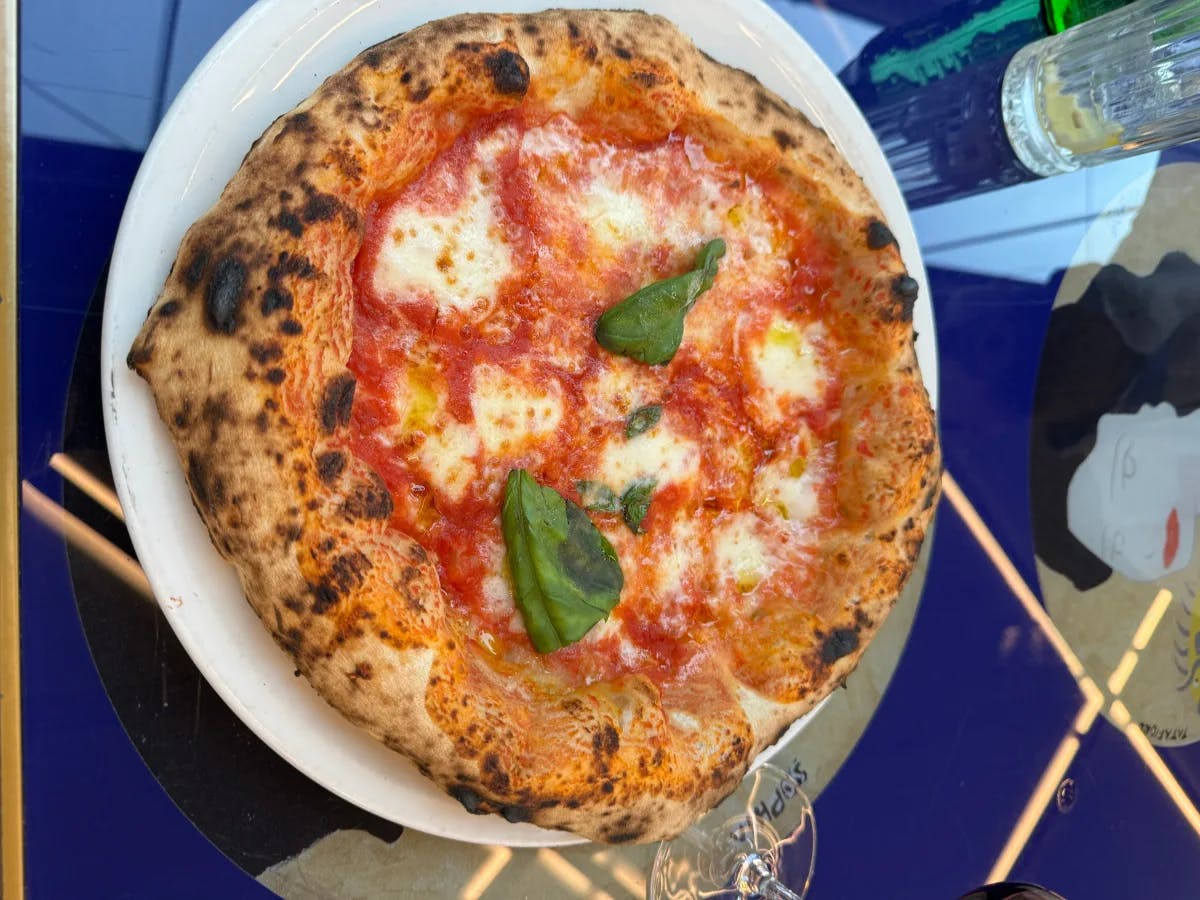 A picture of a pizza served on a white ceramic plate at a restaurant.