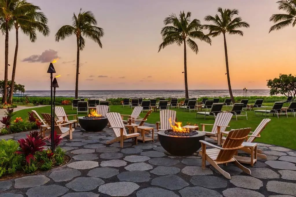 chairs and fire pits sit on an outdoor seating area overlooking the sea