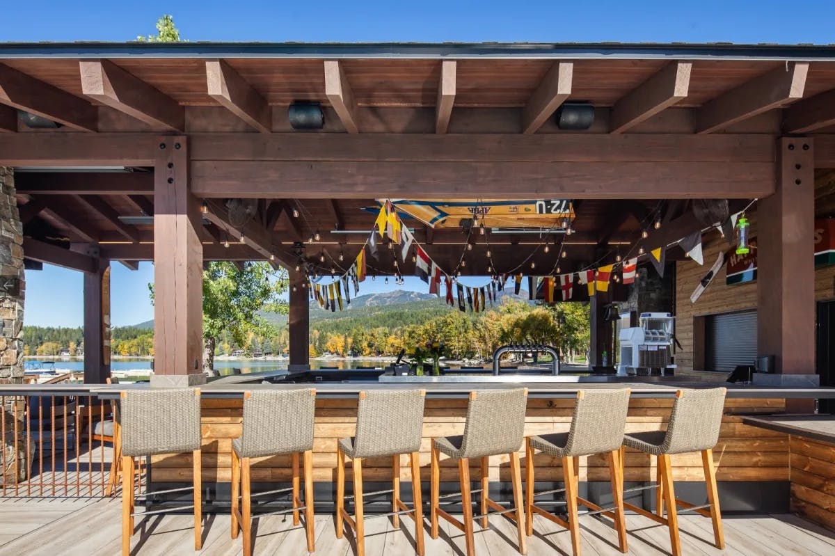 outdoor bar with stools and views of a mountain lake beyond