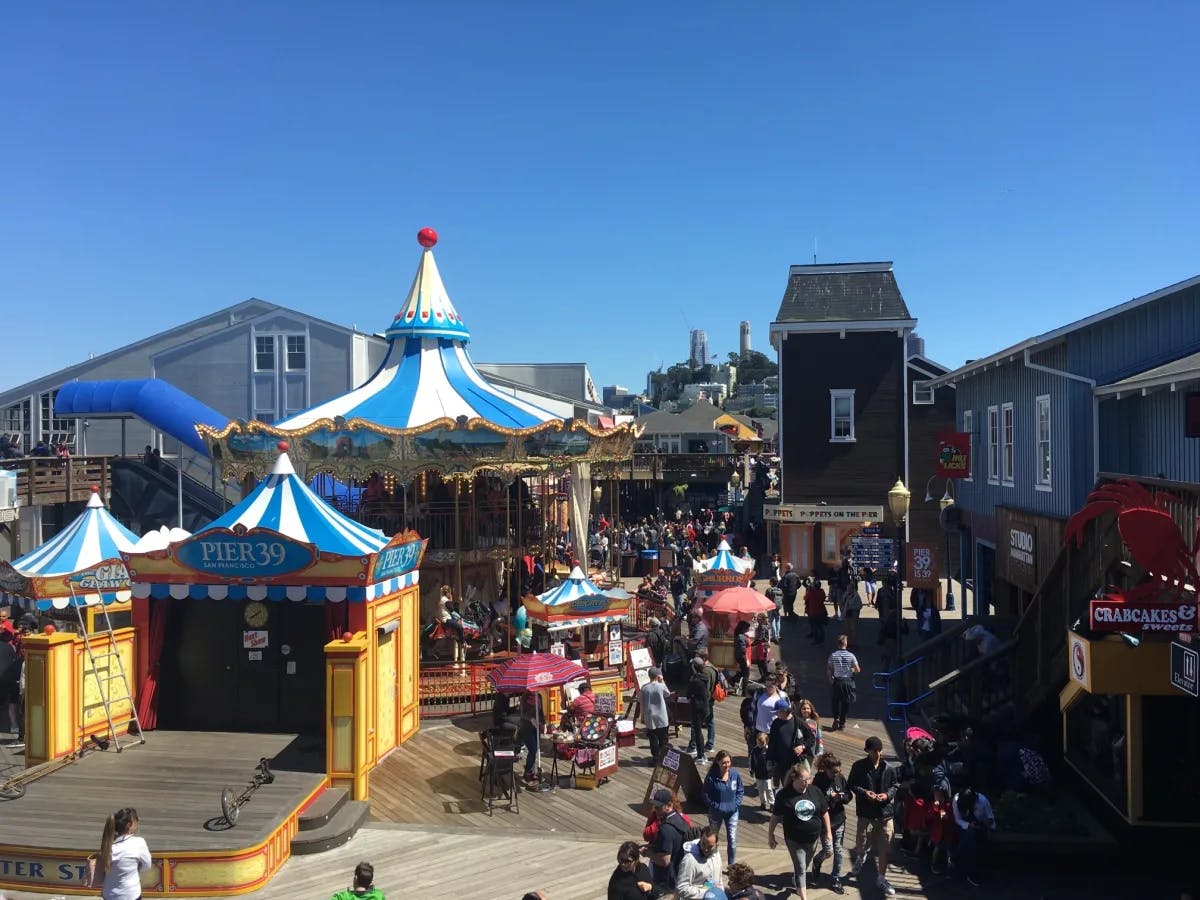 A crowded walking area with games and ride at the pier. 