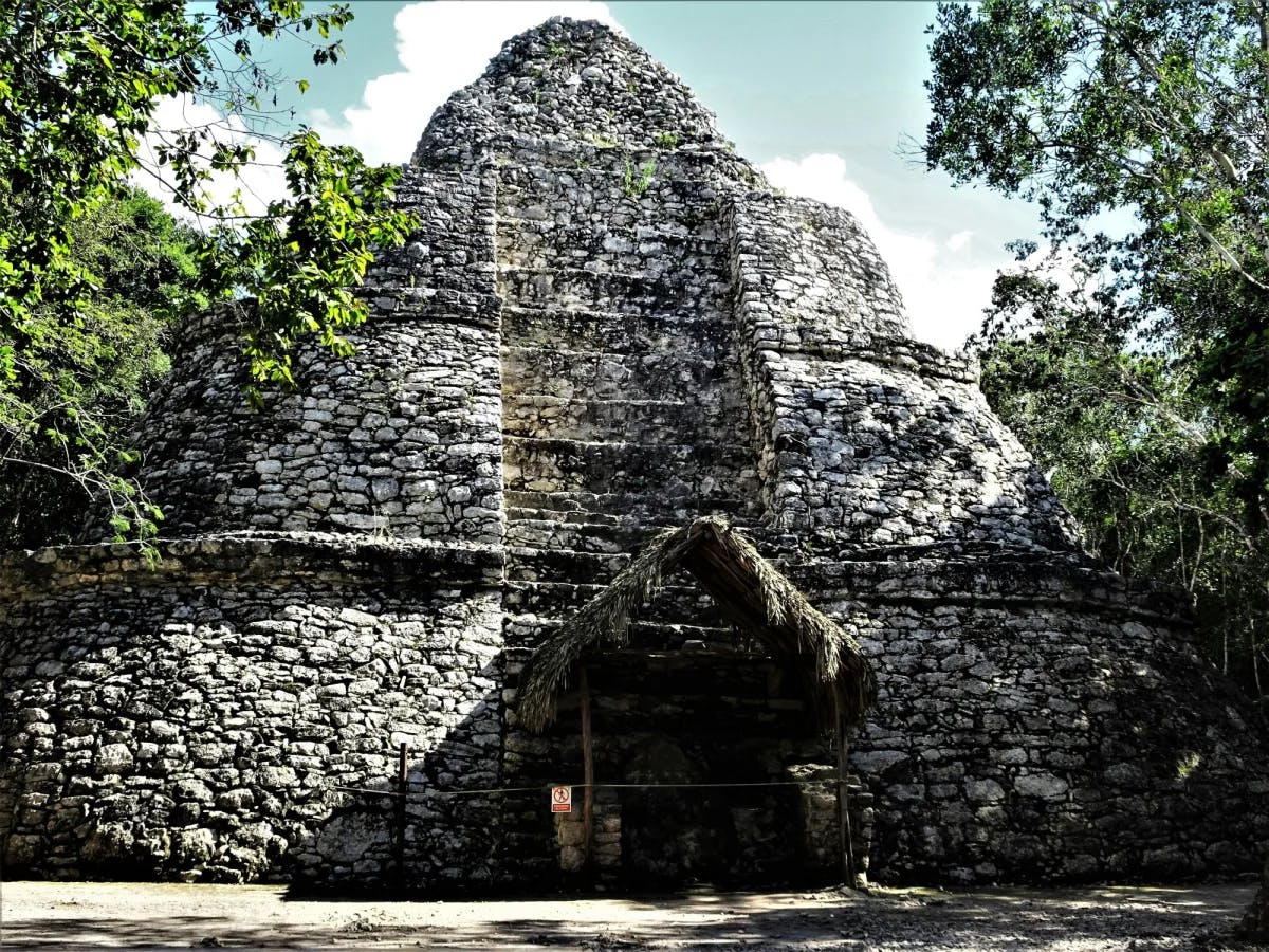 An old stone building with a straw roof and door.