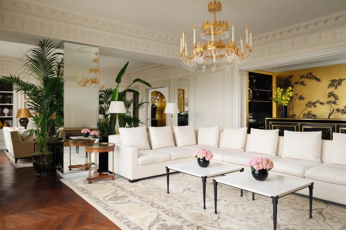 a large L-shaped white couch beneath a gold chandelier in a fancy living room