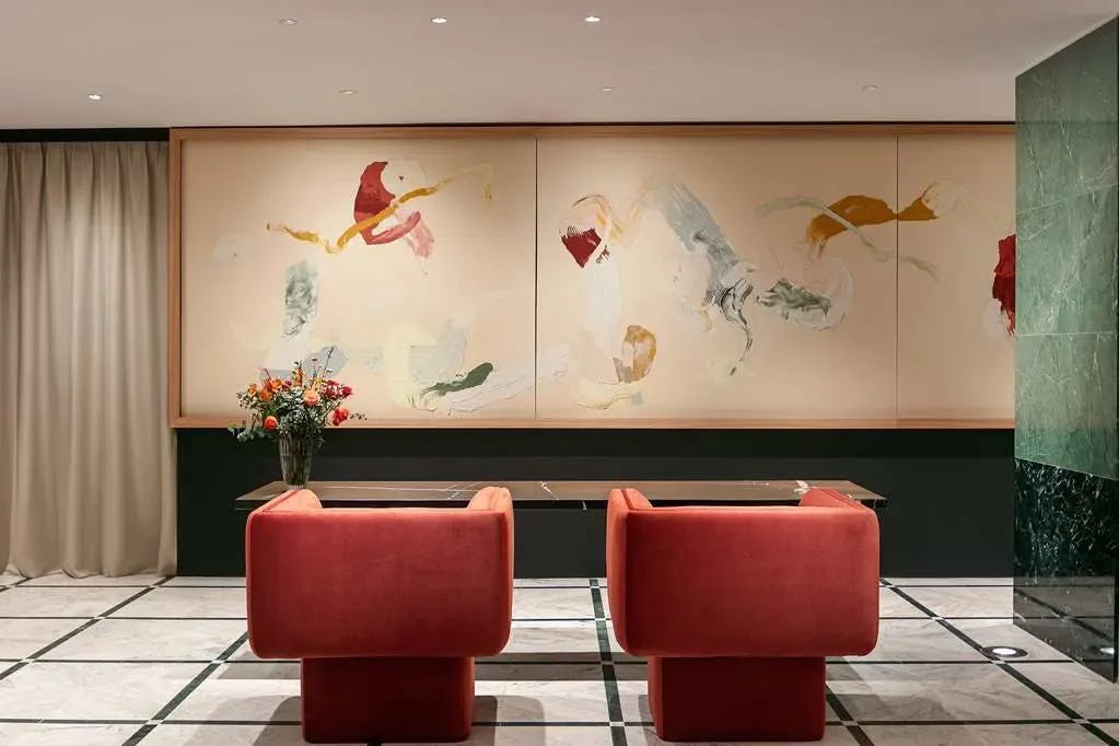 two red chairs in front of a wooden desk in a colorful hotel lobby