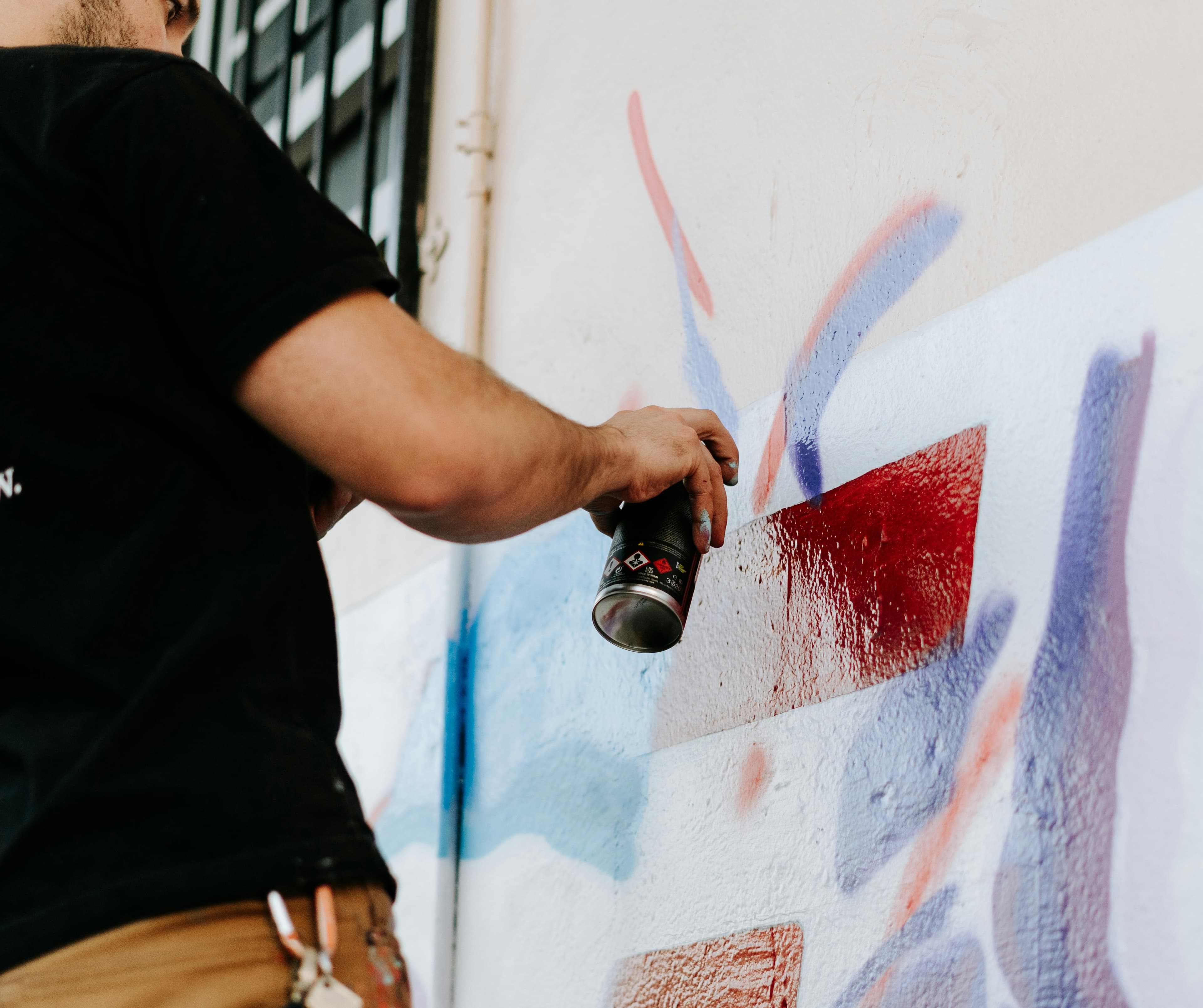 A person spray painting a wall mural