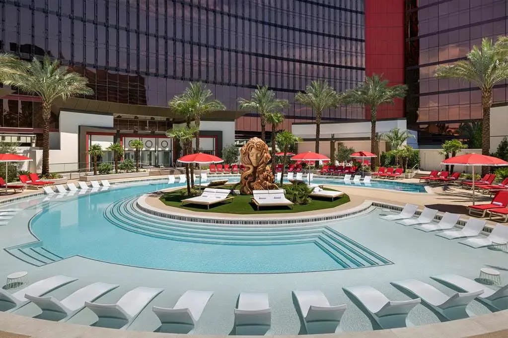 A classical statue of a woman stands prominently in the middle of a sleek, contemporary pool surrounded by loungers and palms at Crockfords Las Vegas