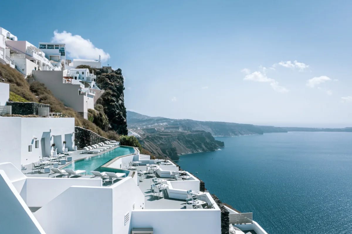 aerial view of a white cliffside hotel in Greece