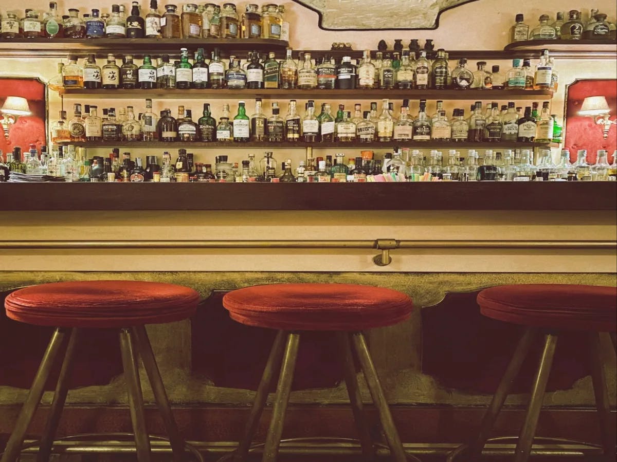 A picture of a bar with shelves of beverages on display.