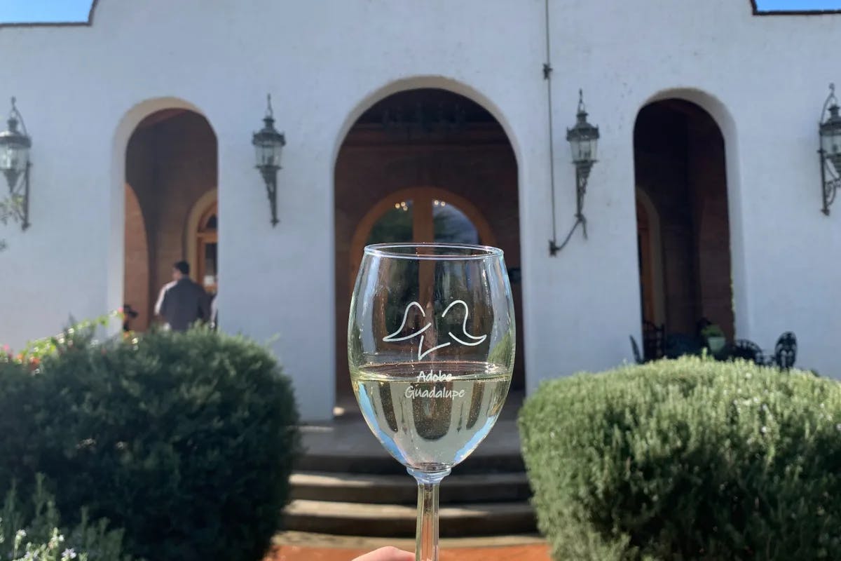 A picture of a wine glass in front of a building during the daytime.