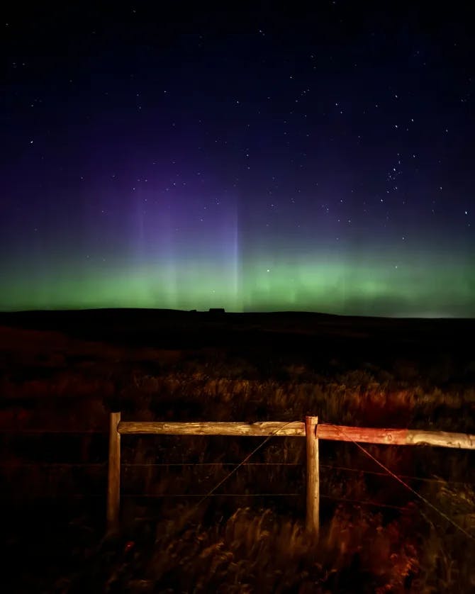 View of a bright green showing of the northern lights on a pitch dark night