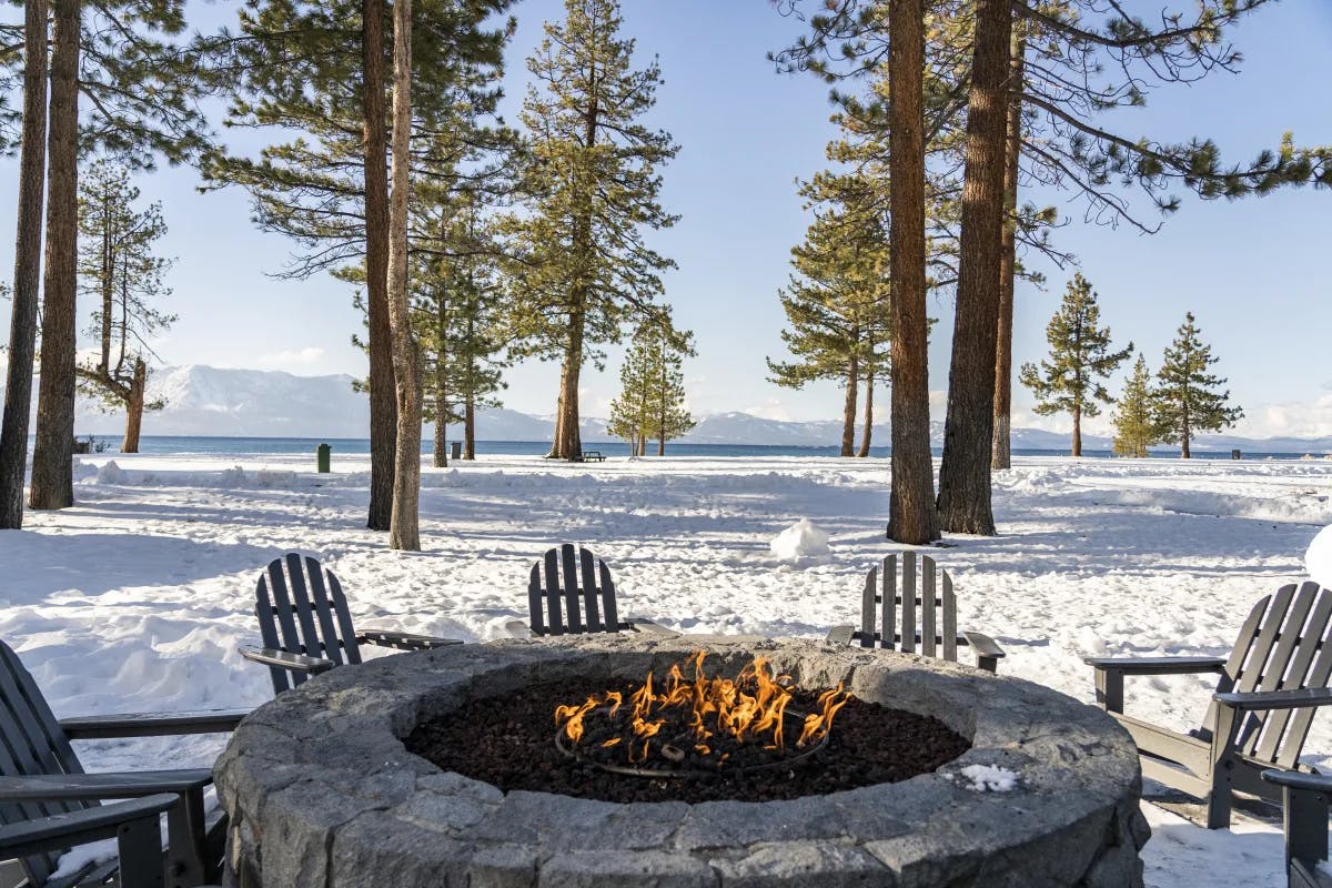 A picture of a firepit with chairs with snowy surroundings.