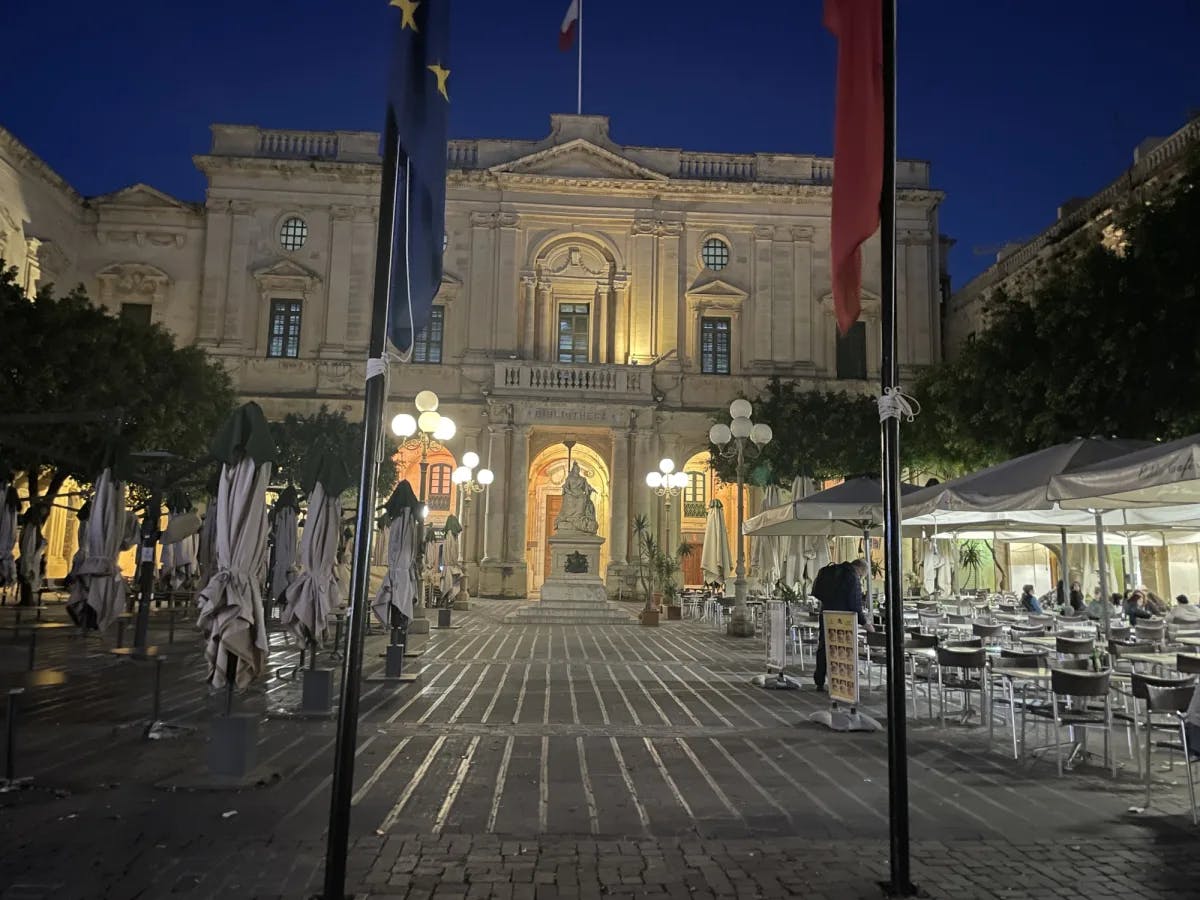 Outdoor sitting of a restaurant in front of a grand white building.