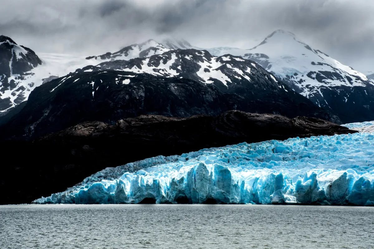 snow-capped mountains and blue glacier ice on the edge of a lake