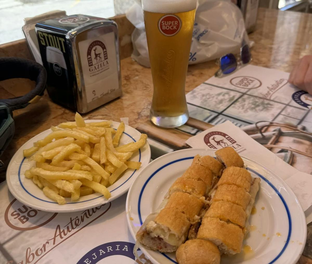 A sandwich, fries and beer on table.