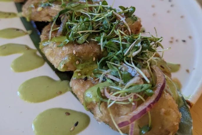 A white plate of food topped with greens.