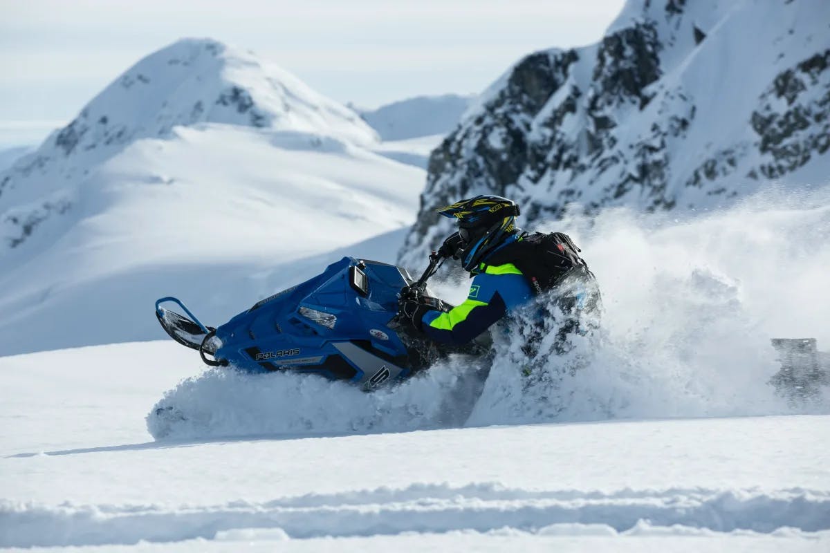 A person on a snowmobile driving through snow 