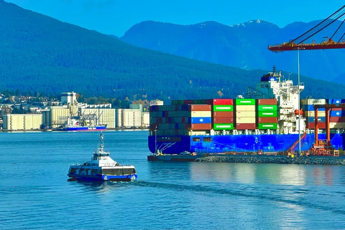 A boat from Seabus is in the water near a large container ship.